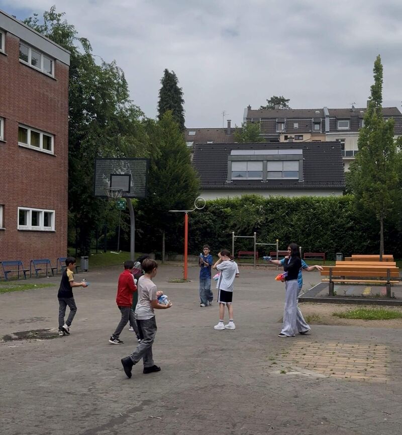 Mit Wasserpistolen und Wasserbomben machen sich acht Schülerinnen und Schüler gegenseitig nass.
