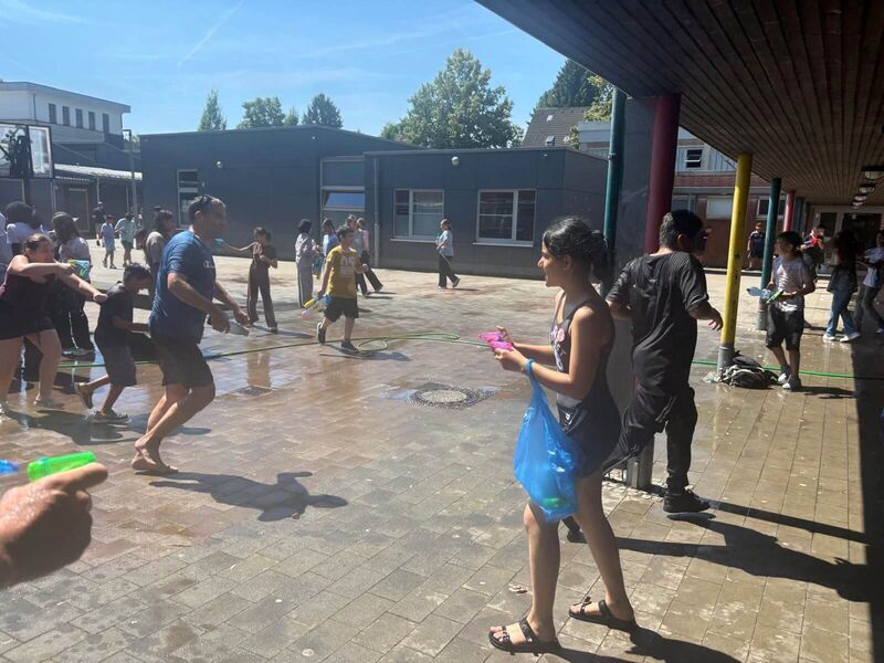 Eine Lehrer verfolgt einen Schüler mit einer Wasserflasche und versucht ihn nass zu machen.
