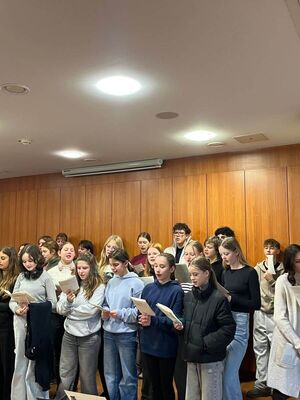 Eine Gruppe von Schülerinnen und Schülern stehen vor einer Wand und singen Weihnachtslieder