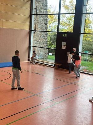 Eine Klasse spielt in einer Sporthalle Fußball.