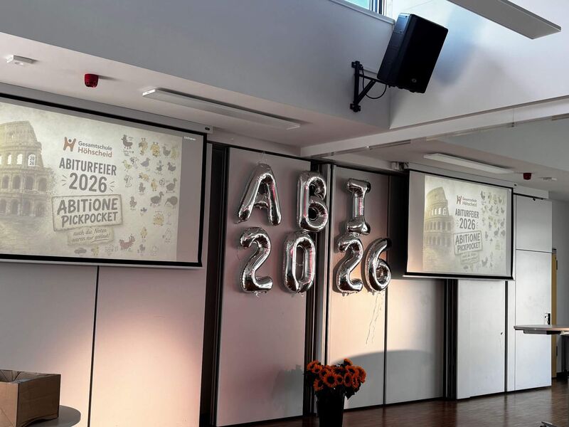 Das Abiturmotto ist an zwei Projektionswänden angeworfen. In der Mitte sind Luftballons mit dem Schriftzug Abi 2026 aufgehangen.
